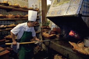 Cocinero asando al horno un cochinillo en la cocina de Casa Botín