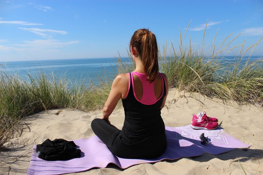 Imagen de una mujer practicando yoga en la playa