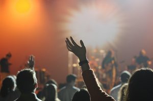 Gente con los brazos levantados en sala de conciertos