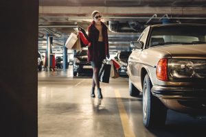 Mujer cargada con bolsas de la compra llegando a un coche