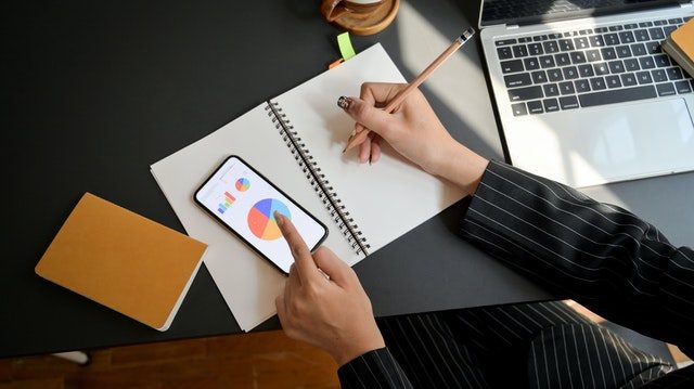 persona escribiendo y tocando la pantalla del movil junto a un ordenador